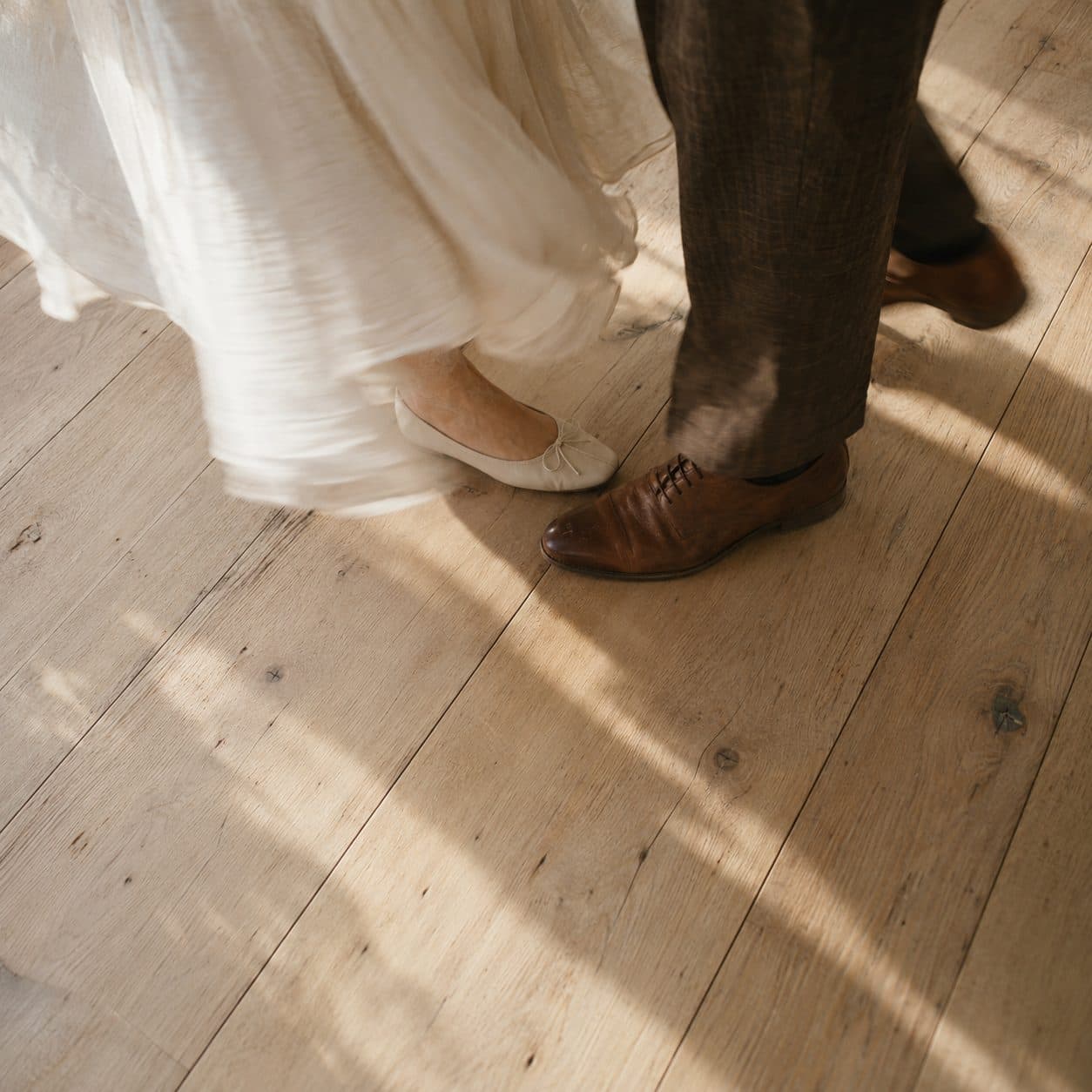Pies de una pareja balanceándose despacio sobre un suelo de madera, ejemplo de baile de novios sencillo