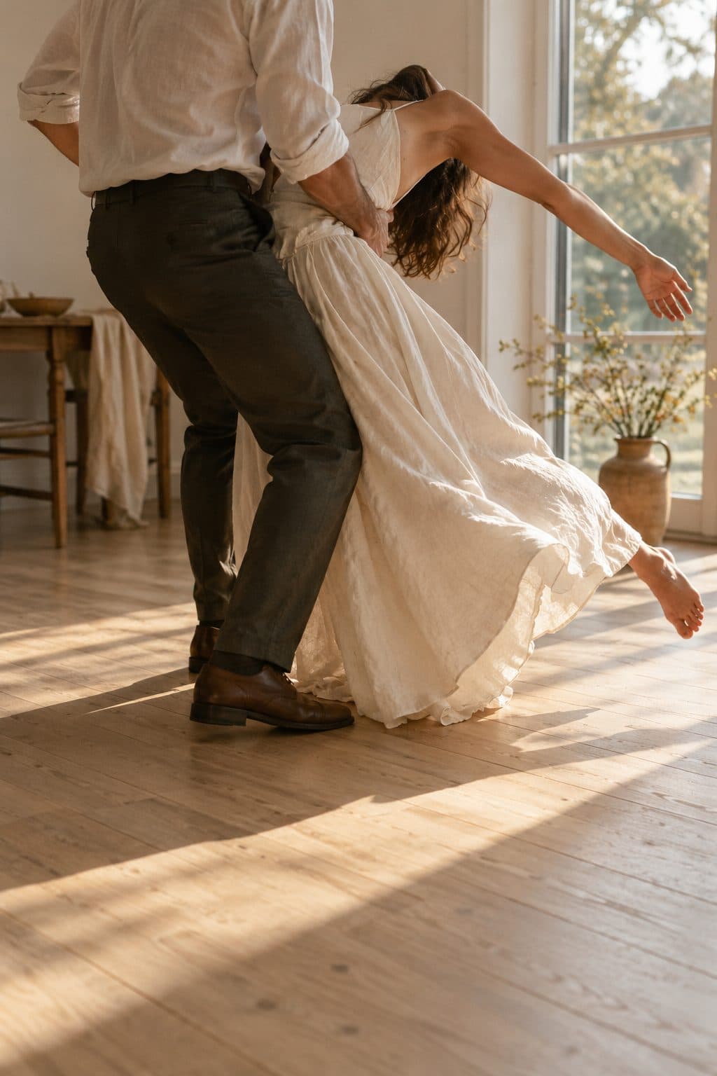 Pareja de espaldas en una postura exagerada y divertida a mitad de un primer baile de boda