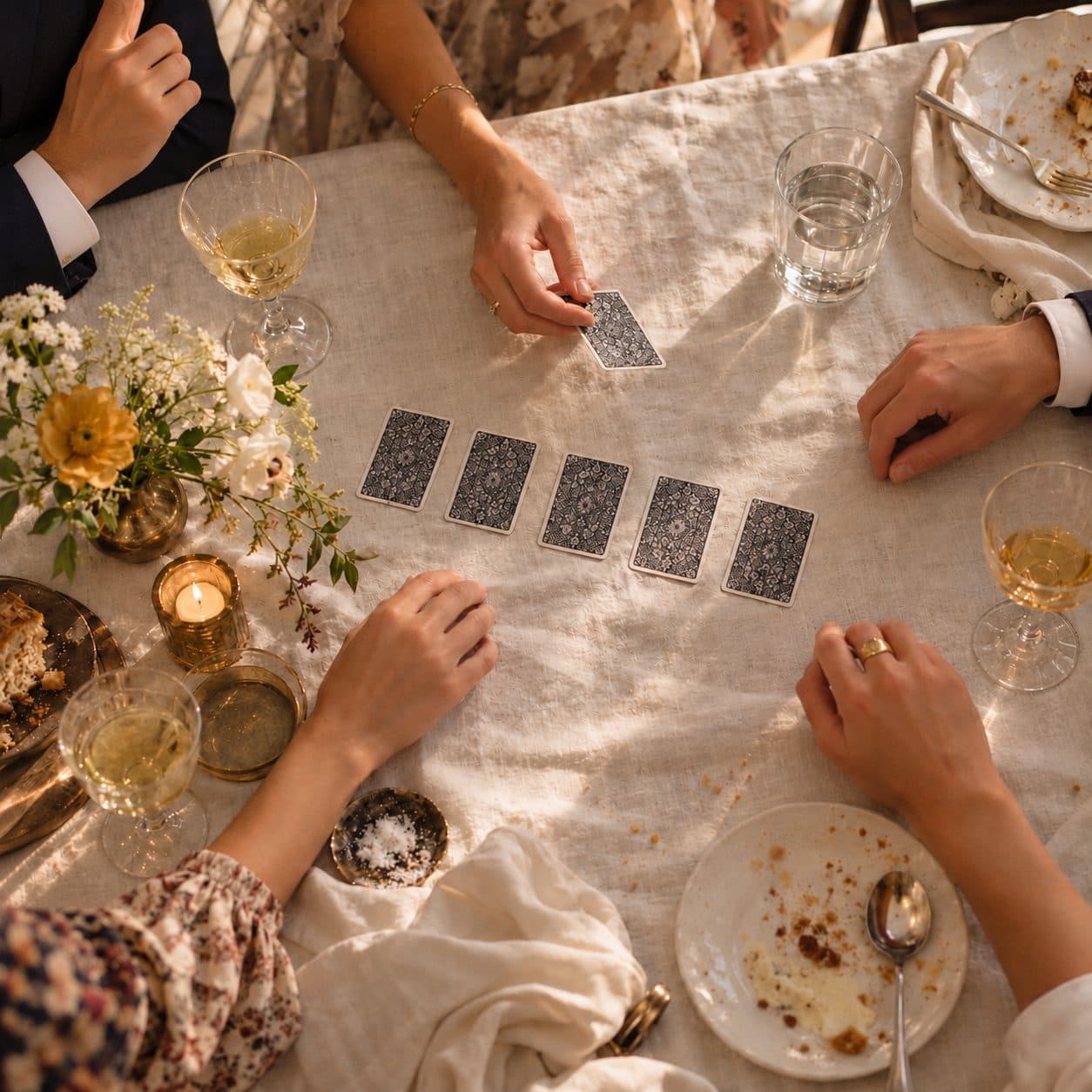 Manos de una mesa de invitados colocando cartas numeradas boca abajo en orden, sin hablar, en el juego de la cuenta callada